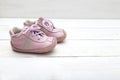 Pink little boots for a girl on a white wooden background