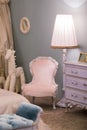 Pink little princess room with a floor lamp by a children`s toy horse and a beautiful chest of drawers, frames on the walls. Luxu Royalty Free Stock Photo