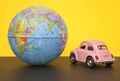 Pink little retro car with world globe sphere. Travel concept. Planning season vacations. Close-up Royalty Free Stock Photo