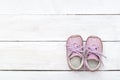 Pink little shoes on a white wooden background