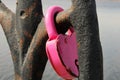 A pink lock in the shape of a heart close-up hangs on a rusty lattice. wedding tradition. The concept of love and