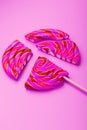 Pink Lollipop split into pieces on a pink background, top view, close-up