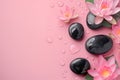 Pink lotus flowers and black spa stones adorned with water droplets, arranged on a pastel pink background. Royalty Free Stock Photo