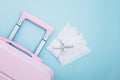 Pink luggage with white airplane model and hygiene face mask on blue background