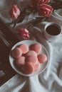 Pink macaron cookies with cup of coffee and rose flowers on white background. Royalty Free Stock Photo