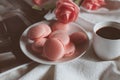 Pink macaron cookies with cup of coffee and rose flowers on white background. Royalty Free Stock Photo