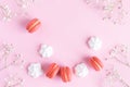 Pink macarons, white marshmallows and flowers on a pink pastel background