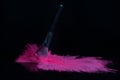 Pink makeup powder brush fall on shiny black surface in a dust cloud Royalty Free Stock Photo