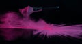 Pink makeup powder brush fall on shiny black surface in a dust cloud Royalty Free Stock Photo