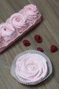 Pink marshmallow in a gift box. Nearby is a bouquet of several raspberries