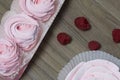 Pink marshmallow in a gift box. Nearby is a bouquet of several raspberries