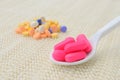 Pink medicine tablet on the spoon and group of colorful medicine tablet Royalty Free Stock Photo