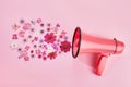 Pink megaphone with colorful flowers on pink background. Minimal nature concept.