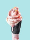 Pink melting ice cream in black waffle cone