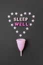 Pink menstrual cup on black background with with heart and words Sleep Well. Concept possibility of use cup at night, zero waste,