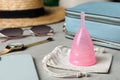 Pink menstrual cup with cotton bag and women`s accessories on white wooden table Royalty Free Stock Photo