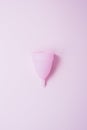 Pink menstrual cup on a pastel background. Vertical photo. Trendy feminine sanitary product. Flat lay, top view