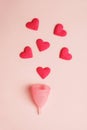 pink menstrual cup and red hearts as blood drops isolated on rose background, menstruation cycle, women gynecological health and Royalty Free Stock Photo