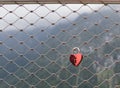 Pink metal padlock on the gray patterned metal lattice fence