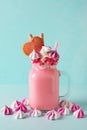 Pink milkshake with cream, marshmallow candy hearts on blue background Royalty Free Stock Photo