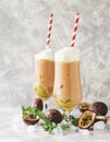 Pink milkshake with ice cubes and mint leaves and fruits of passion fruit on a marble table, selective focus Royalty Free Stock Photo