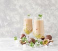 Pink milkshake with ice cubes and mint leaves and fruits of passion fruit on a marble table, selective focus Royalty Free Stock Photo