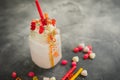 Pink milkshake with whipped cream, dripping sauce and candy`s on table Royalty Free Stock Photo