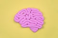 Pink model of human brain profile view on yellow background, flat lay. Intelligence concept.