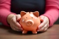 Pink money piggy bank being held by child\'s hands