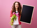 Smiling young woman with bouquet of tulips showing black board Royalty Free Stock Photo