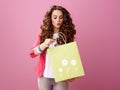 Surprised woman isolated on pink looking in shopping bag Royalty Free Stock Photo