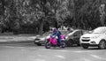 Pink motorcyclist standing out among balck and white cars