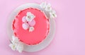 Pink mousse cake with mirror glaze decorated with macaroons, flowers for Happy Birthday on pink holiday background