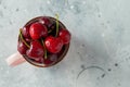 Pink mug with fresh ripe cherries. Sweet organic berries on a light concrete background. Top view with copy space Royalty Free Stock Photo