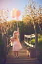 Pink is my most favorite color. a unrecognizable little girl holding balloons and a teddy bear while standing in the Royalty Free Stock Photo