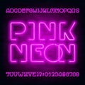 Pink Neon alphabet font. Modern light bulb letters and numbers on brick wall background. Royalty Free Stock Photo