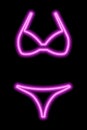 Pink neon silhouette of a women's swimsuit on a black background. Bikini Royalty Free Stock Photo