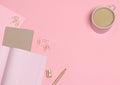 Pink note with golden pencil, paper clips, sharpener and coffee cup on pink background