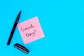 Pink note with inscription Good day and marker on blue background, flat lay. Royalty Free Stock Photo