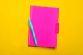 Pink notebook and pen on yellow background, top view Royalty Free Stock Photo