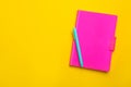 Pink notebook and pen on yellow background. Space for text Royalty Free Stock Photo