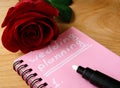 Pink notepad with wedding planning and rose.