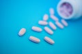 Pink oblong tablets spilled on a blue background. Medicine and health. Shallow depth of field