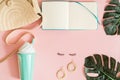 Pink office table with cup of coffee, flowers, macarons, pen, pencil, make up brush, notebook and empty paper. Woman`s accessorie