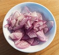 Pink onion in a bowl on wooden table. Top view