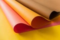 Pink and orange papers rolled together over yellow color paper. Papers for creative craft and design in school