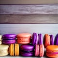 Pink, orange, purple and yellow macarons on a light wooden background