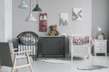 Pink organizer on wall of trendy baby bedroom with two cribs and chest of drawers Royalty Free Stock Photo