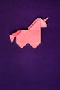 Pink origami unicorn on dark ultra violet background