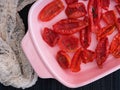 Pink oven dish with sun dried tomatoes. Black napkin background